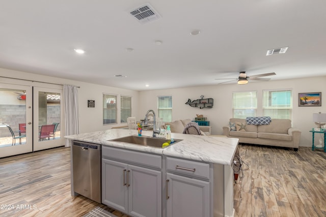 kitchen featuring dishwasher, an island with sink, sink, and light hardwood / wood-style flooring