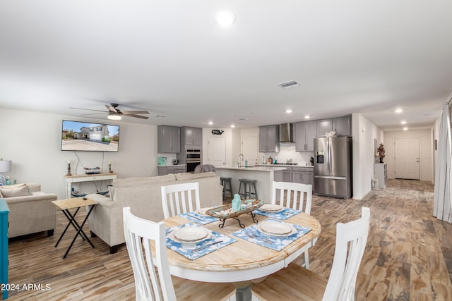 dining room with ceiling fan, sink, and light hardwood / wood-style floors