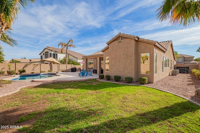 rear view of house with a lawn, a fenced backyard, a tiled roof, a patio area, and stucco siding