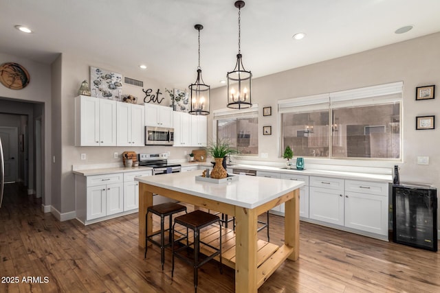 kitchen featuring visible vents, appliances with stainless steel finishes, decorative light fixtures, light countertops, and white cabinetry