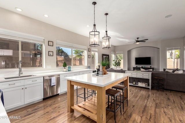 kitchen with light countertops, open floor plan, white cabinetry, a sink, and dishwasher