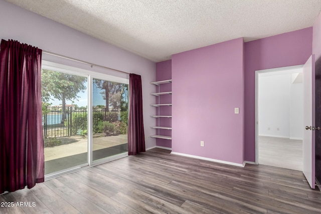 unfurnished room with baseboards, a textured ceiling, and wood finished floors