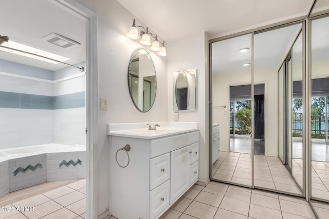 full bathroom featuring tile patterned floors, visible vents, vanity, and tiled bath