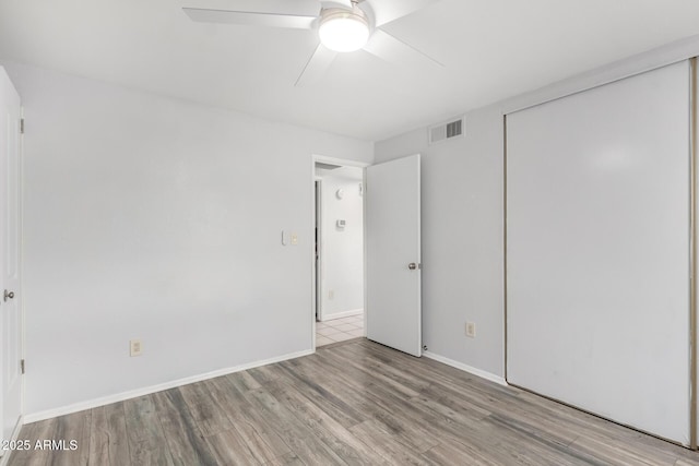 unfurnished bedroom featuring visible vents, light wood-style flooring, a ceiling fan, a closet, and baseboards