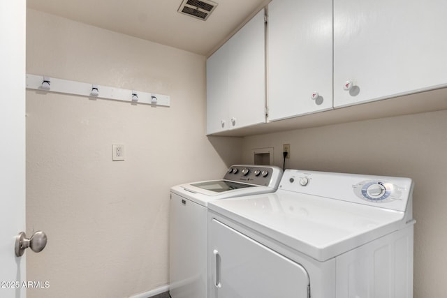 laundry room featuring washing machine and clothes dryer, visible vents, and cabinet space