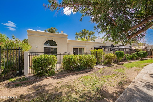 view of front of property featuring a chimney, a fenced front yard, and stucco siding