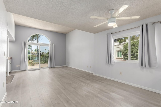 spare room with a healthy amount of sunlight, baseboards, light wood finished floors, and ceiling fan