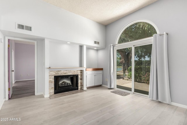 unfurnished living room with light wood-style flooring, visible vents, and a wealth of natural light