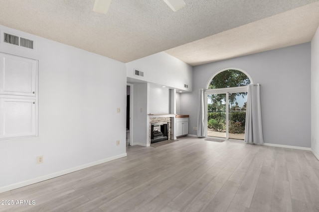 unfurnished living room featuring visible vents, a fireplace with flush hearth, baseboards, and light wood-style flooring