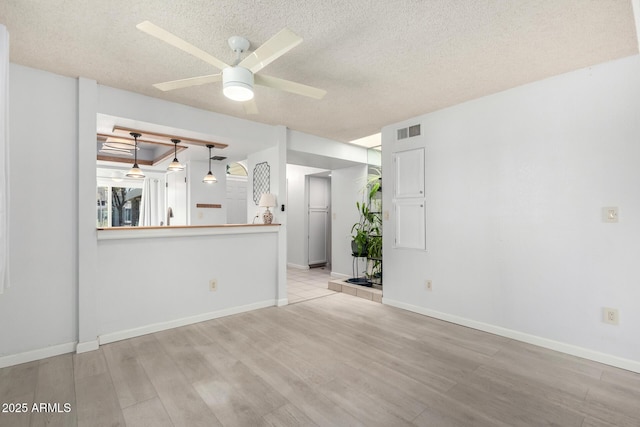 spare room with ceiling fan, wood finished floors, visible vents, and a textured ceiling