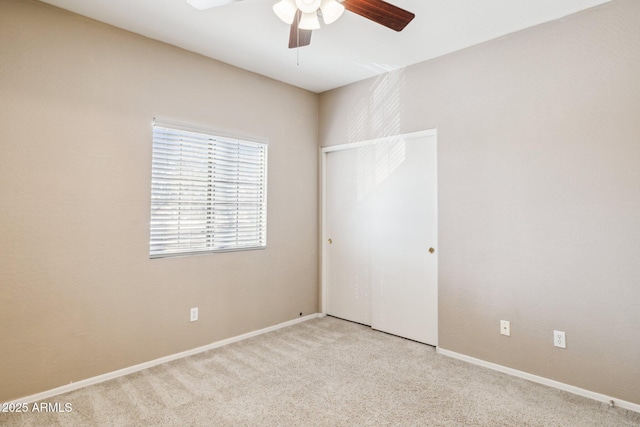 unfurnished bedroom with ceiling fan, a closet, baseboards, and light colored carpet