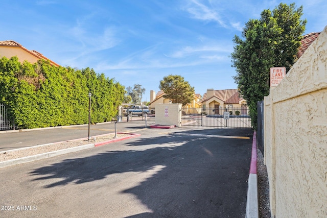 view of road with street lighting, a gated entry, curbs, traffic signs, and a gate