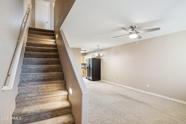 stairs featuring baseboards, a ceiling fan, and carpet flooring