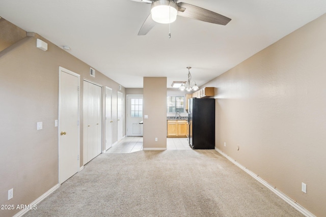 empty room with light carpet, a sink, visible vents, and baseboards