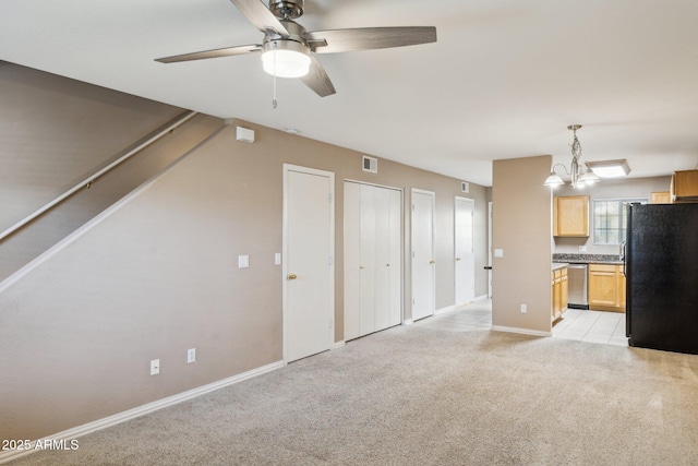 unfurnished living room featuring light carpet, ceiling fan with notable chandelier, visible vents, baseboards, and stairs