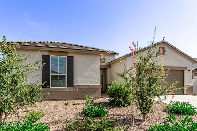view of front of house featuring a tile roof, stucco siding, and a garage