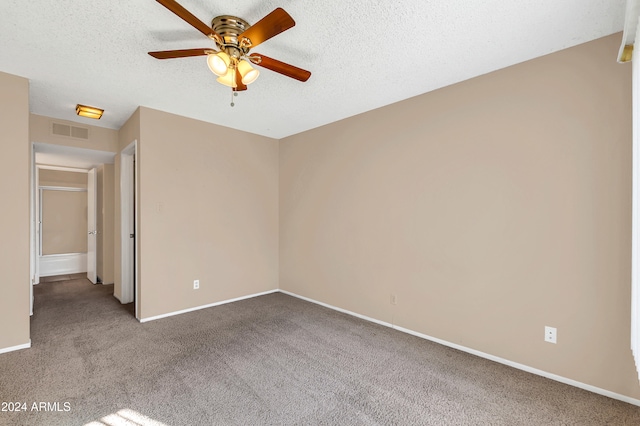 carpeted empty room featuring ceiling fan and a textured ceiling