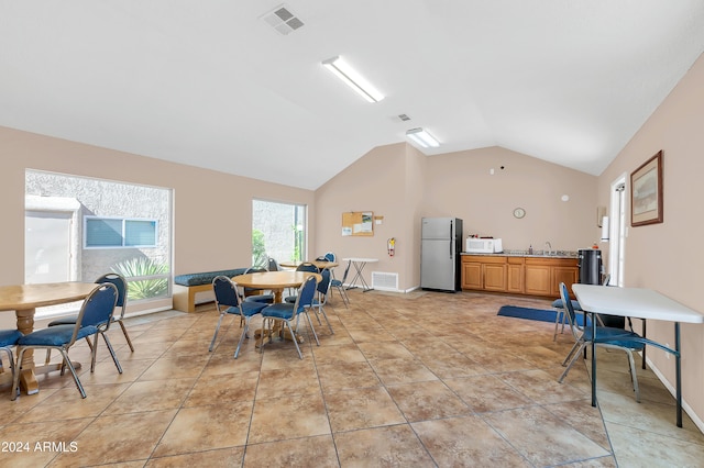 dining space featuring high vaulted ceiling and light tile patterned floors