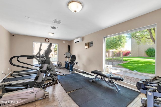 workout room with an AC wall unit and light tile patterned floors