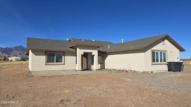 back of property with a mountain view and a patio area