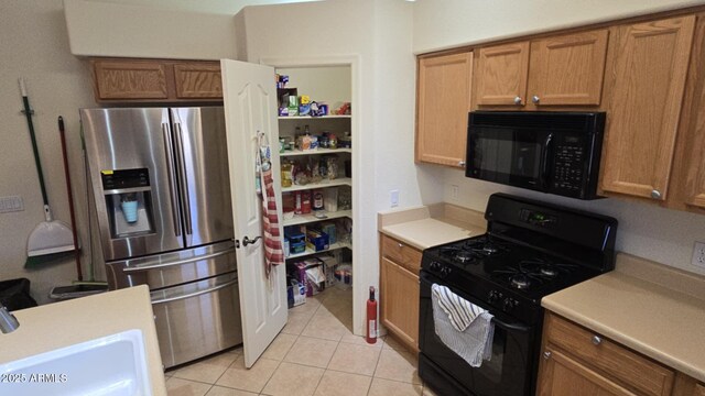 kitchen featuring sink, light tile patterned floors, and black appliances