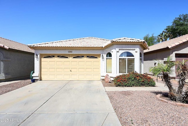 mediterranean / spanish-style home with stucco siding, a tile roof, a garage, and concrete driveway