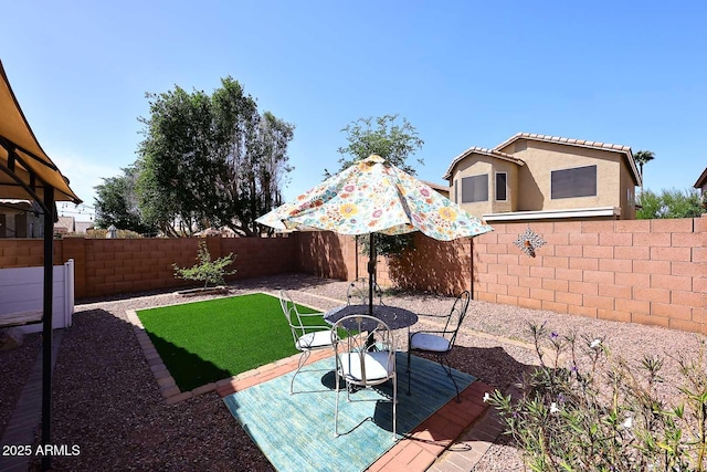 view of yard featuring outdoor dining area and a fenced backyard
