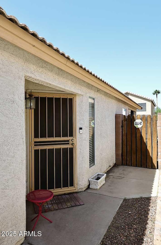 doorway to property featuring stucco siding, a gate, and a tile roof