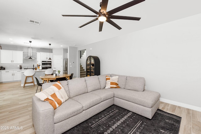 living room with ceiling fan and light hardwood / wood-style flooring