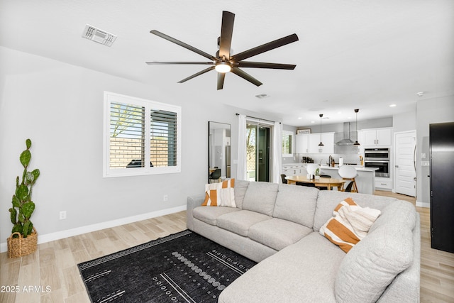 living room featuring a wealth of natural light, light hardwood / wood-style floors, and ceiling fan