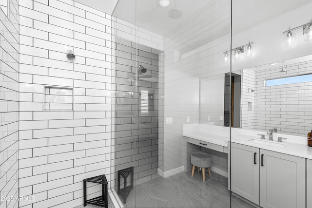 bathroom with a tile shower, vanity, and tile walls