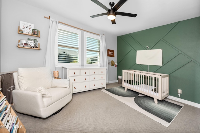 bedroom featuring a nursery area, carpet floors, and ceiling fan