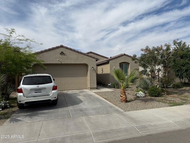 mediterranean / spanish-style house featuring an attached garage, stucco siding, a tile roof, and concrete driveway