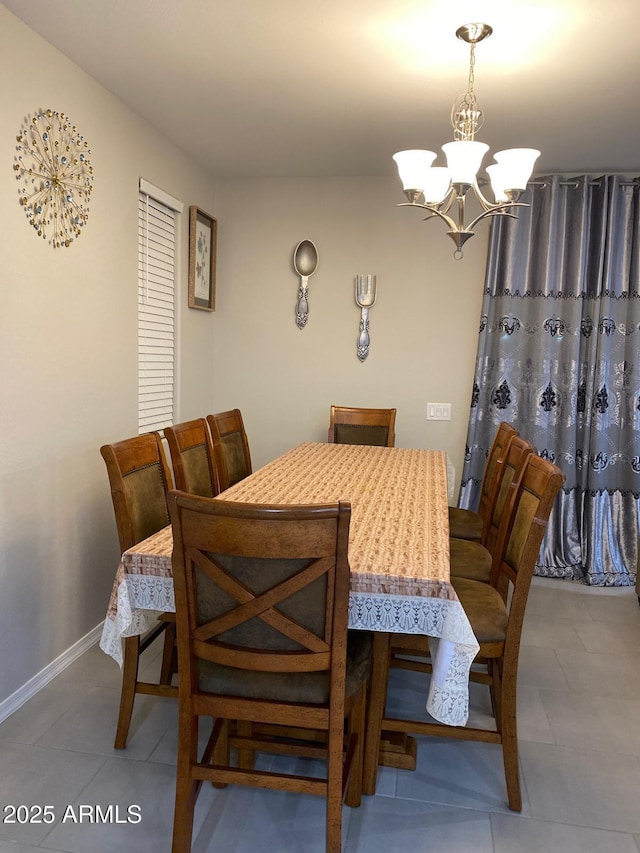 dining area featuring tile patterned flooring, baseboards, and a chandelier
