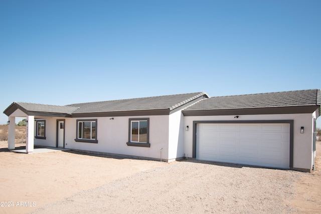 ranch-style house featuring a garage, driveway, a tile roof, and stucco siding