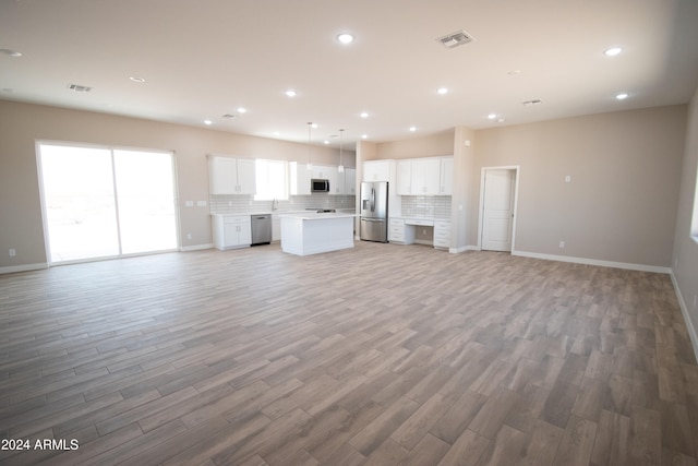 kitchen with visible vents, a kitchen island, open floor plan, stainless steel appliances, and backsplash