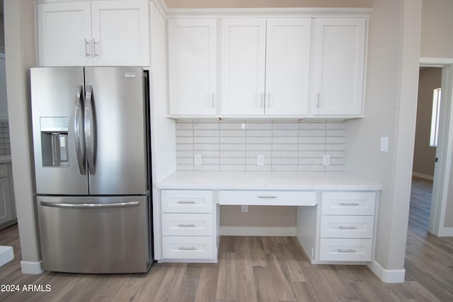 kitchen with tasteful backsplash, light countertops, built in desk, and stainless steel fridge with ice dispenser