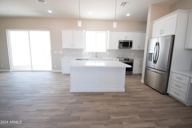 kitchen with stainless steel appliances, white cabinetry, visible vents, light countertops, and decorative backsplash