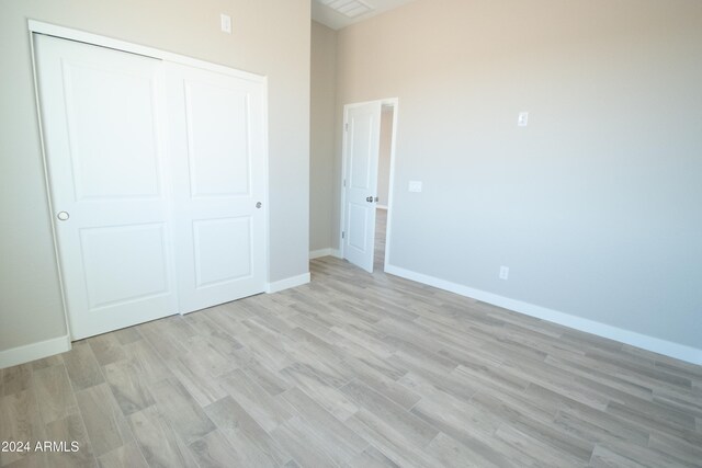 unfurnished bedroom featuring light wood finished floors, baseboards, and a closet