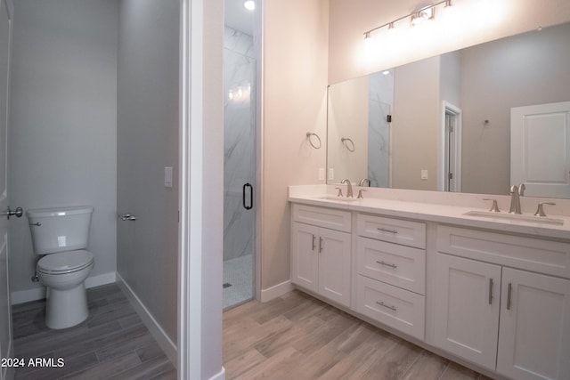 bathroom with toilet, a sink, a marble finish shower, and wood finished floors