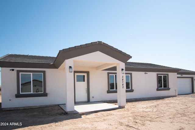 rear view of house featuring a garage and stucco siding