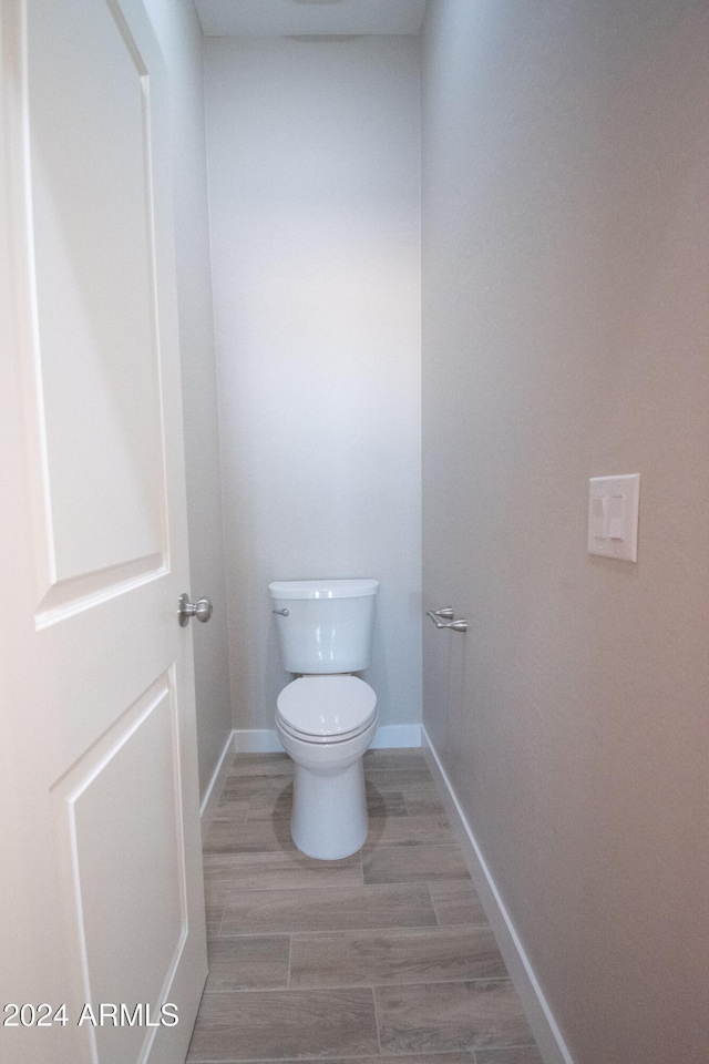 bathroom featuring wood tiled floor, toilet, and baseboards