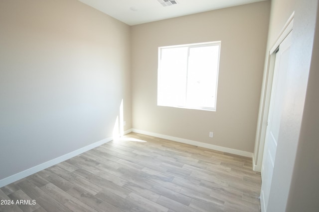 empty room with light wood-style floors, visible vents, and baseboards