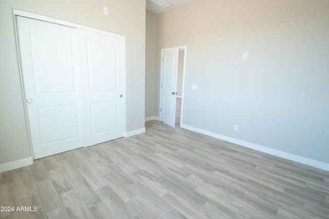 unfurnished bedroom featuring light wood-style floors, a closet, and baseboards