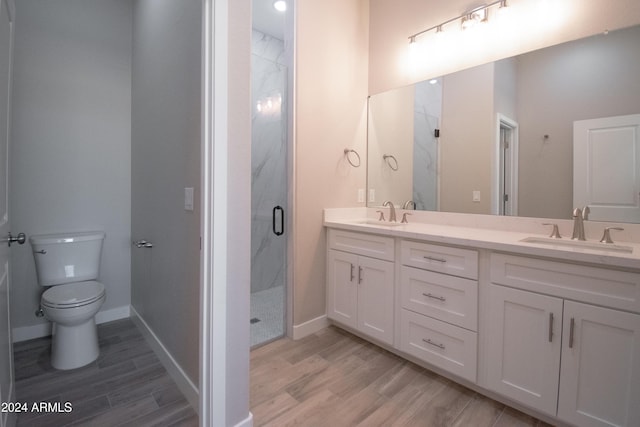 bathroom with toilet, wood finished floors, a sink, and a marble finish shower