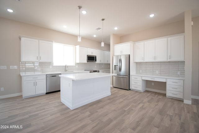 kitchen with stainless steel appliances, built in desk, a sink, and white cabinets