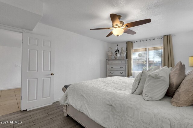 bedroom featuring ceiling fan, hardwood / wood-style floors, and a textured ceiling