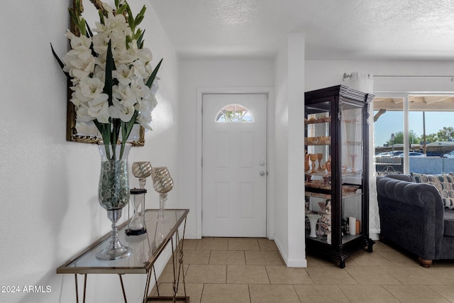 foyer entrance with light tile patterned floors and a textured ceiling