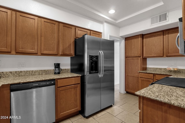 kitchen featuring light tile patterned flooring, a raised ceiling, light stone countertops, and stainless steel appliances