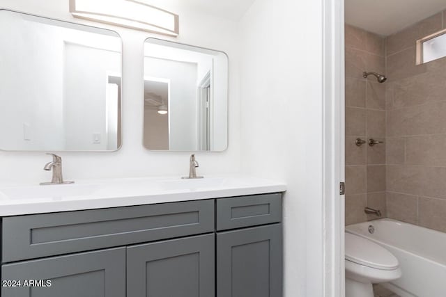 full bathroom featuring vanity, tiled shower / bath combo, and toilet